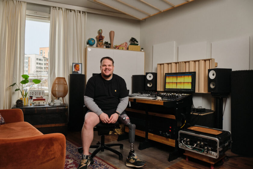 Kuvassa Janne Hakanen, palveluntarjoaja. Istuu studiolaitteiston edessä ja hymyilee.