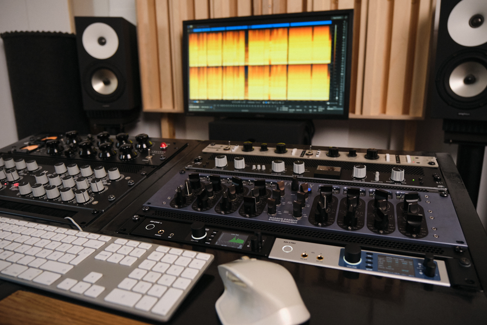 Kuvassa äänistudio, äänilaitteistoa: Manley Massive Passive, RME ADI-2 Pro, Custom Audio Germany HDE-250 EQ, IGS Audio Tubecore 3U -kompressori, TK Audio BC1 -kompressori, Overstayer MAS Rotary, Amphion kaiuttimet, tietokoneen näyttölaite, jossa avoinna Izotope RX -ohjelmisto.