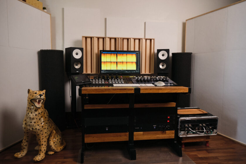 Kuvassa äänistudio, äänilaitteistoa: Manley Massive Passive, RME ADI-2 Pro, Custom Audio Germany HDE-250 EQ, IGS Audio Tubecore 3U -kompressori, TK Audio BC1 -kompressori, Overstayer MAS Rotary, Amphion kaiuttimet, tietokoneen näyttölaite, jossa avoinna Izotope RX -ohjelmisto. Studiopöydän vieressä posliinen pantteripatsas, lisäräkki, jossa Universal Audio -äänikortti. Pöydän ympärillä raskaita akustiikkaelementtejä.
