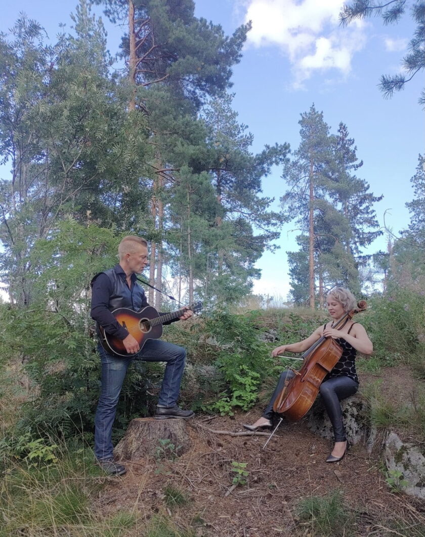 Duo sävy soittamassa sellistin istuessa kivellä, kitaristin säestäessä seisoma-asennossa.