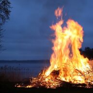 Suomalainen kansanperinne juhannuskokko järven rannalla kesäyössä.
