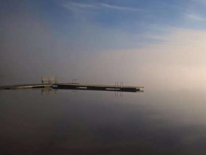 Aamusumussa tyynen järven rannalla oleva laituri.