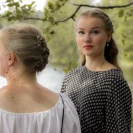 Kaksi henkilöä, toisen kasvot kameraa kohti. Taustalla järvimaisema.